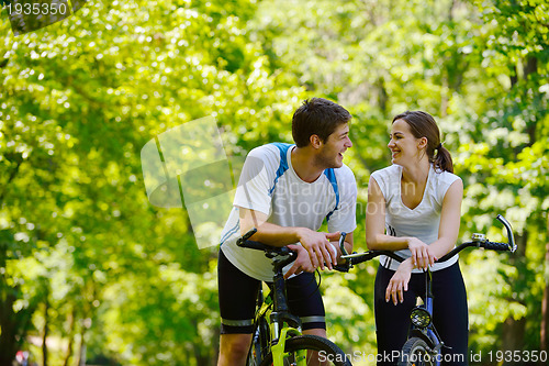 Image of Happy couple riding bicycle outdoors