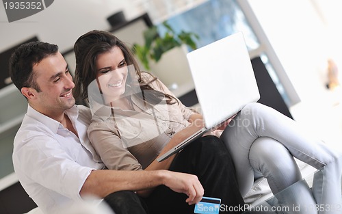 Image of joyful couple relax and work on laptop computer at modern home