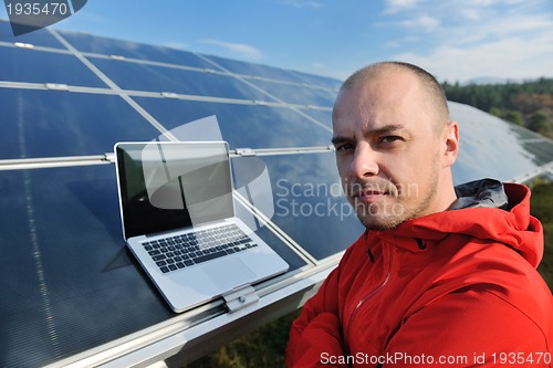 Image of engineer using laptop at solar panels plant field