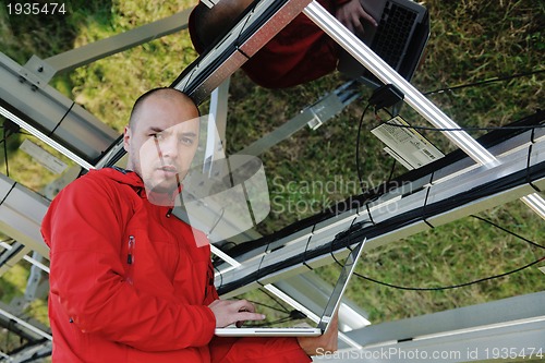 Image of engineer using laptop at solar panels plant field