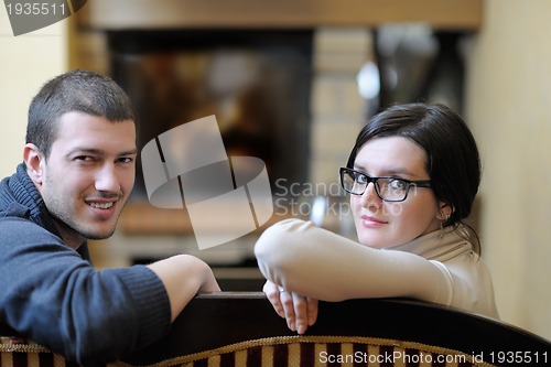 Image of Young romantic couple sitting and relaxing in front of fireplace