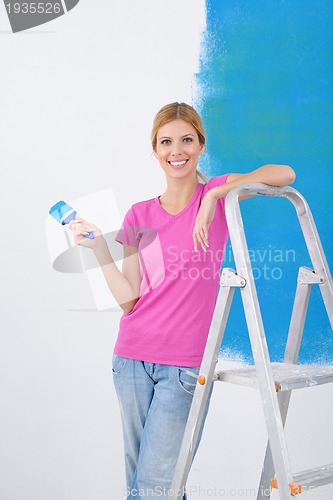 Image of happy smiling woman painting interior of house