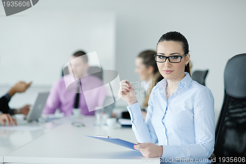 Image of business woman standing with her staff in background