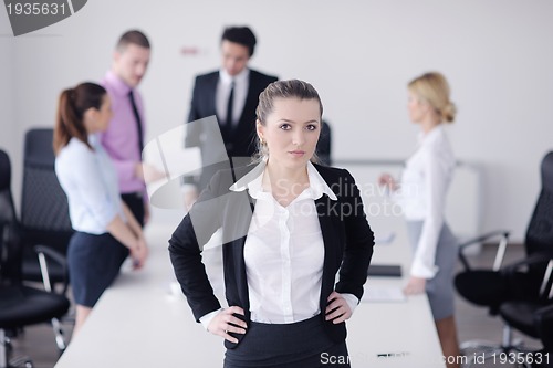 Image of business woman standing with her staff in background