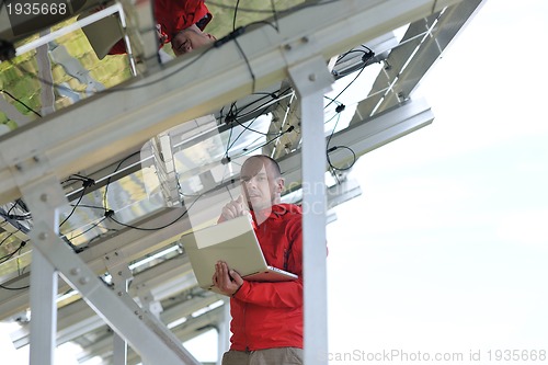 Image of engineer using laptop at solar panels plant field