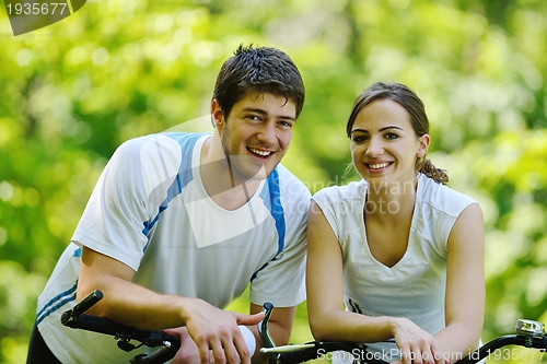 Image of Happy couple riding bicycle outdoors