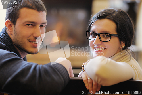 Image of Young romantic couple relax on sofa in front of fireplace at hom