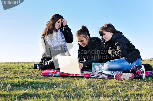 Image of group of teens working on laptop outdoor