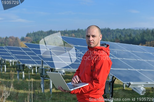 Image of engineer using laptop at solar panels plant field