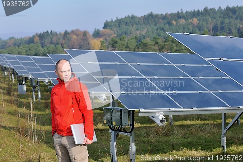 Image of engineer using laptop at solar panels plant field