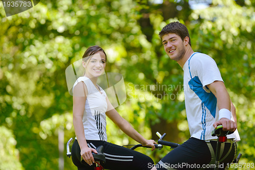 Image of Happy couple riding bicycle outdoors