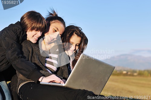 Image of group of teens working on laptop outdoor