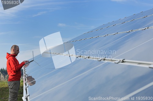 Image of engineer using laptop at solar panels plant field