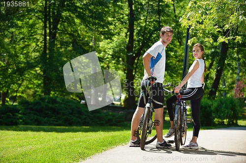 Image of Happy couple riding bicycle outdoors
