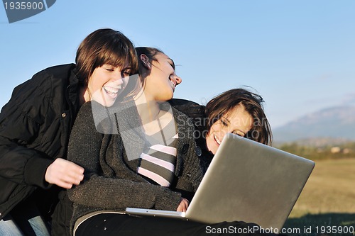 Image of group of teens working on laptop outdoor