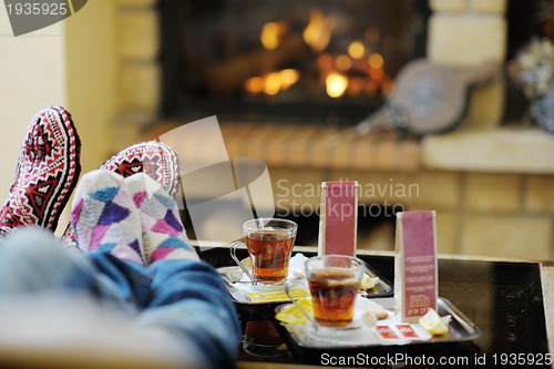 Image of Young romantic couple sitting and relaxing in front of fireplace