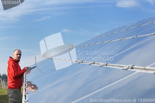 Image of engineer using laptop at solar panels plant field