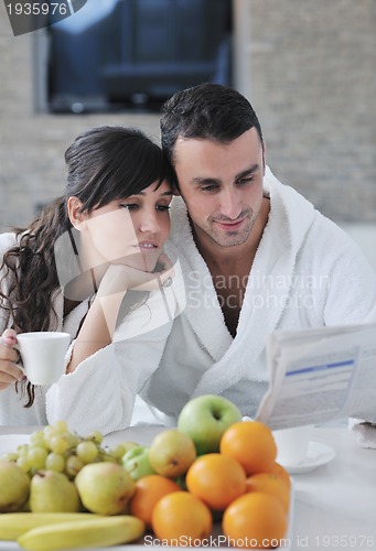 Image of Happy couple reading the newspaper in the kitchen at breakfast