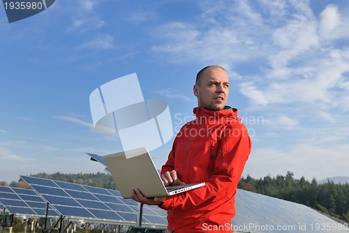 Image of engineer using laptop at solar panels plant field