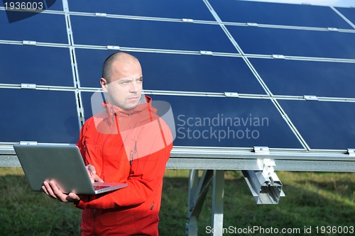 Image of engineer using laptop at solar panels plant field