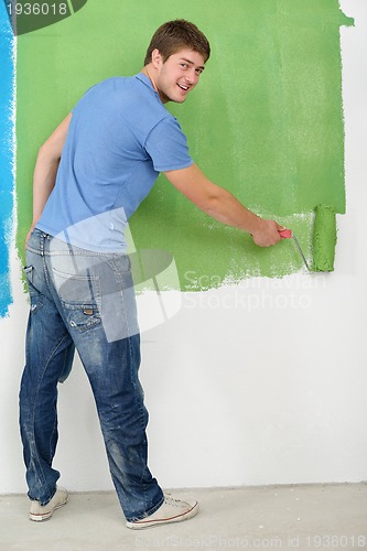 Image of handsome young man paint white wall in color
