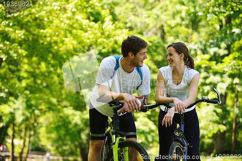Image of Happy couple riding bicycle outdoors