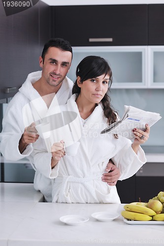 Image of Happy couple reading the newspaper in the kitchen at breakfast