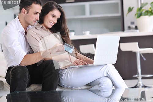 Image of joyful couple relax and work on laptop computer at modern home