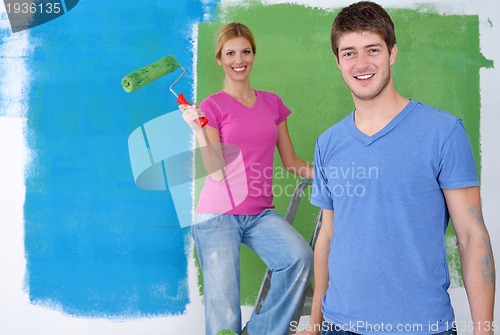 Image of happy couple paint wall at new home