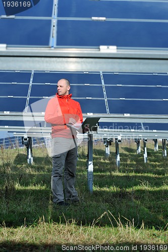 Image of engineer using laptop at solar panels plant field