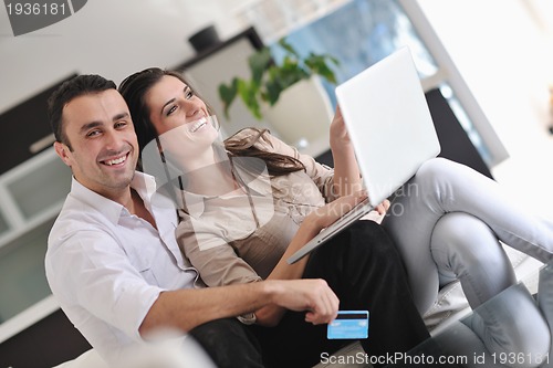 Image of joyful couple relax and work on laptop computer at modern home