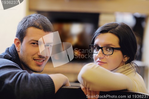 Image of Young romantic couple sitting and relaxing in front of fireplace