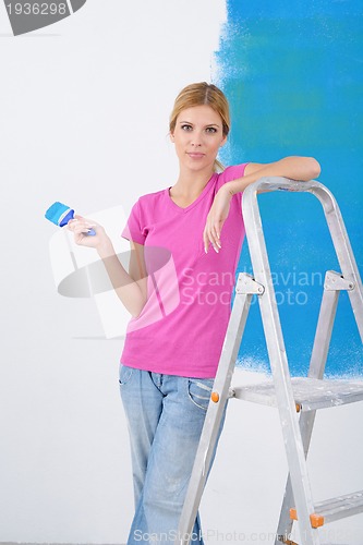 Image of happy smiling woman painting interior of house