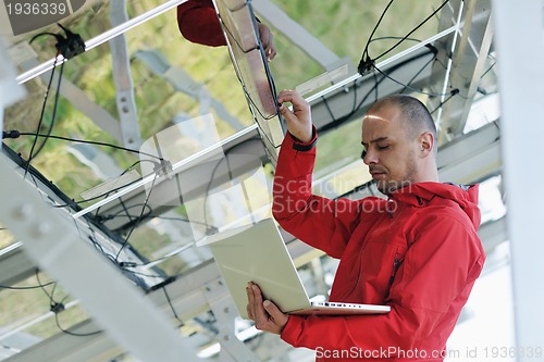 Image of engineer using laptop at solar panels plant field