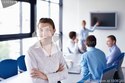 Image of business woman with her staff in background at office