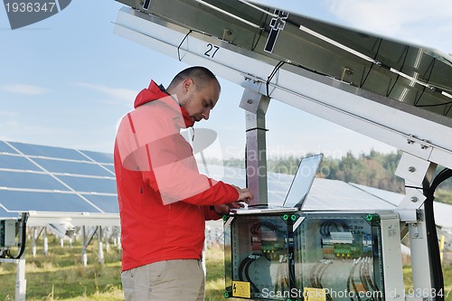 Image of engineer using laptop at solar panels plant field