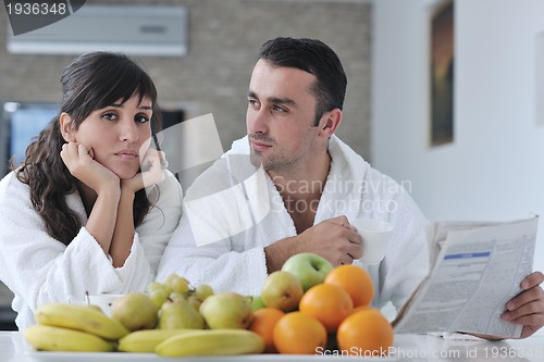Image of Happy couple reading the newspaper in the kitchen at breakfast