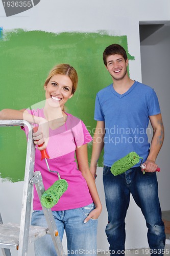 Image of happy couple paint wall at new home