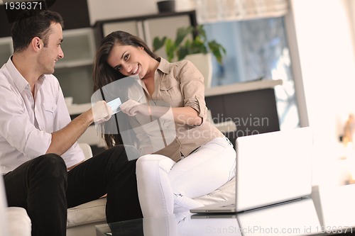 Image of joyful couple relax and work on laptop computer at modern home
