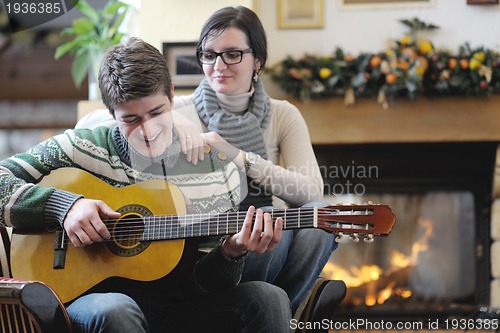 Image of Young romantic couple sitting and relaxing in front of fireplace