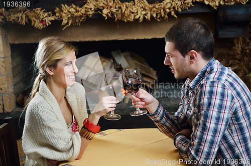 Image of Young romantic couple sitting on sofa in front of fireplace at h