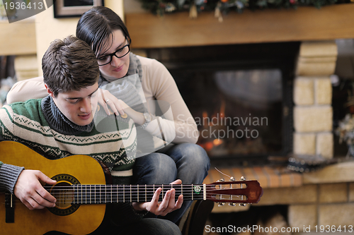 Image of Young romantic couple sitting on sofa in front of fireplace at h