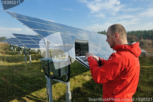 Image of engineer using laptop at solar panels plant field