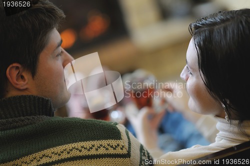 Image of Young romantic couple sitting and relaxing in front of fireplace