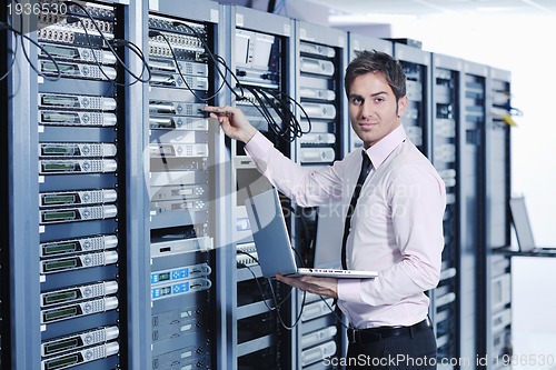 Image of businessman with laptop in network server room