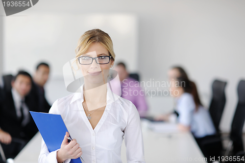 Image of business woman standing with her staff in background