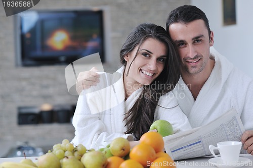 Image of Happy couple reading the newspaper in the kitchen at breakfast