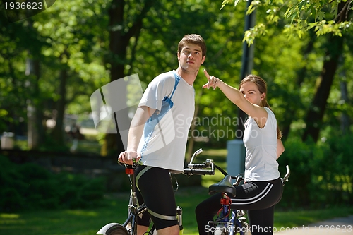 Image of Happy couple riding bicycle outdoors