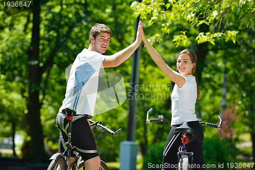 Image of Happy couple riding bicycle outdoors