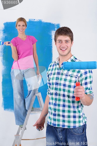 Image of happy couple paint wall at new home